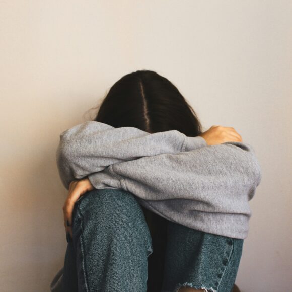 Girl with head down in folded arms